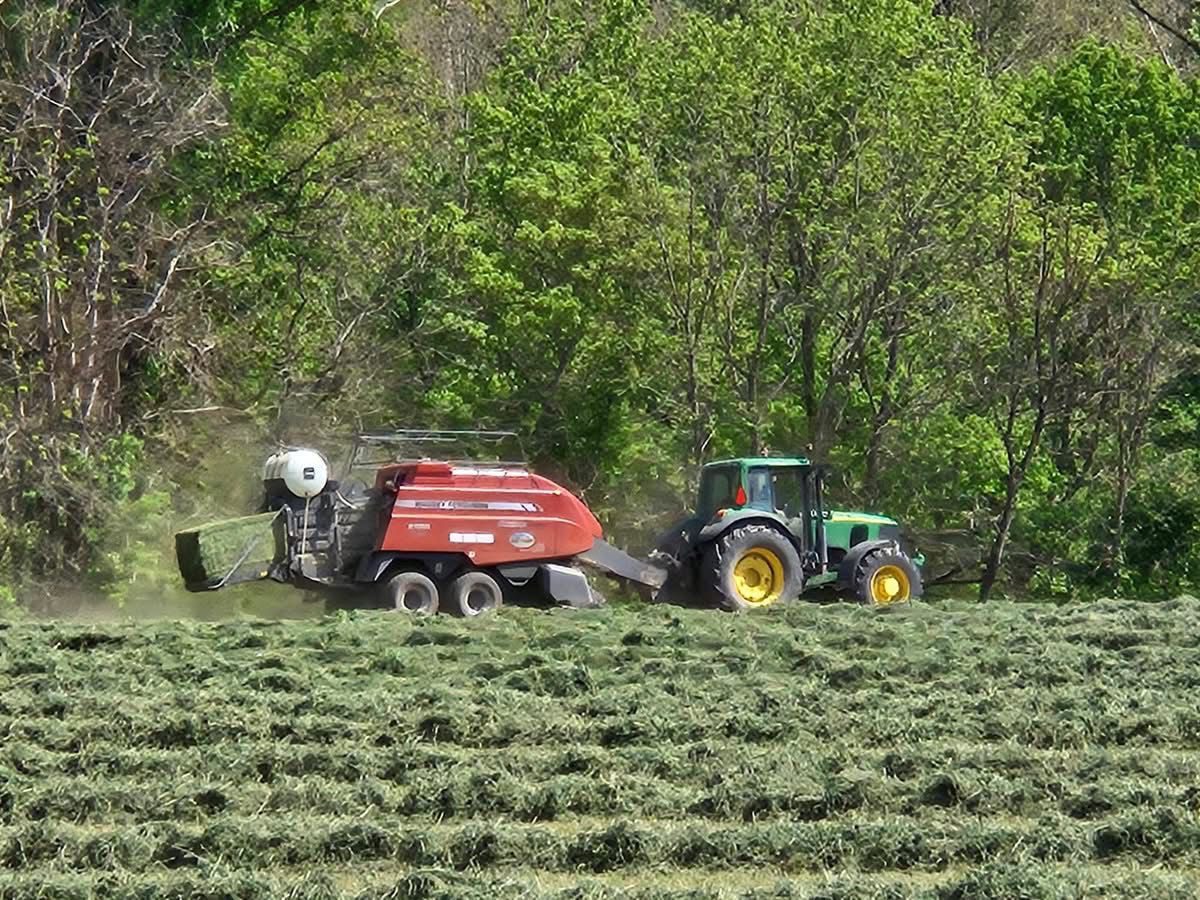 Tractor pulling baler across hay field